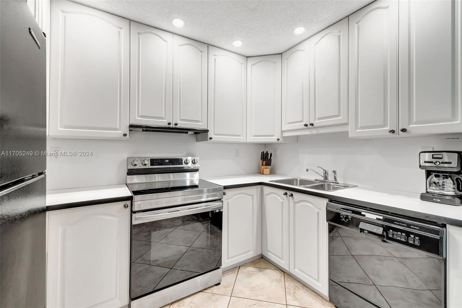 a kitchen with granite countertop white cabinets and stainless steel appliances