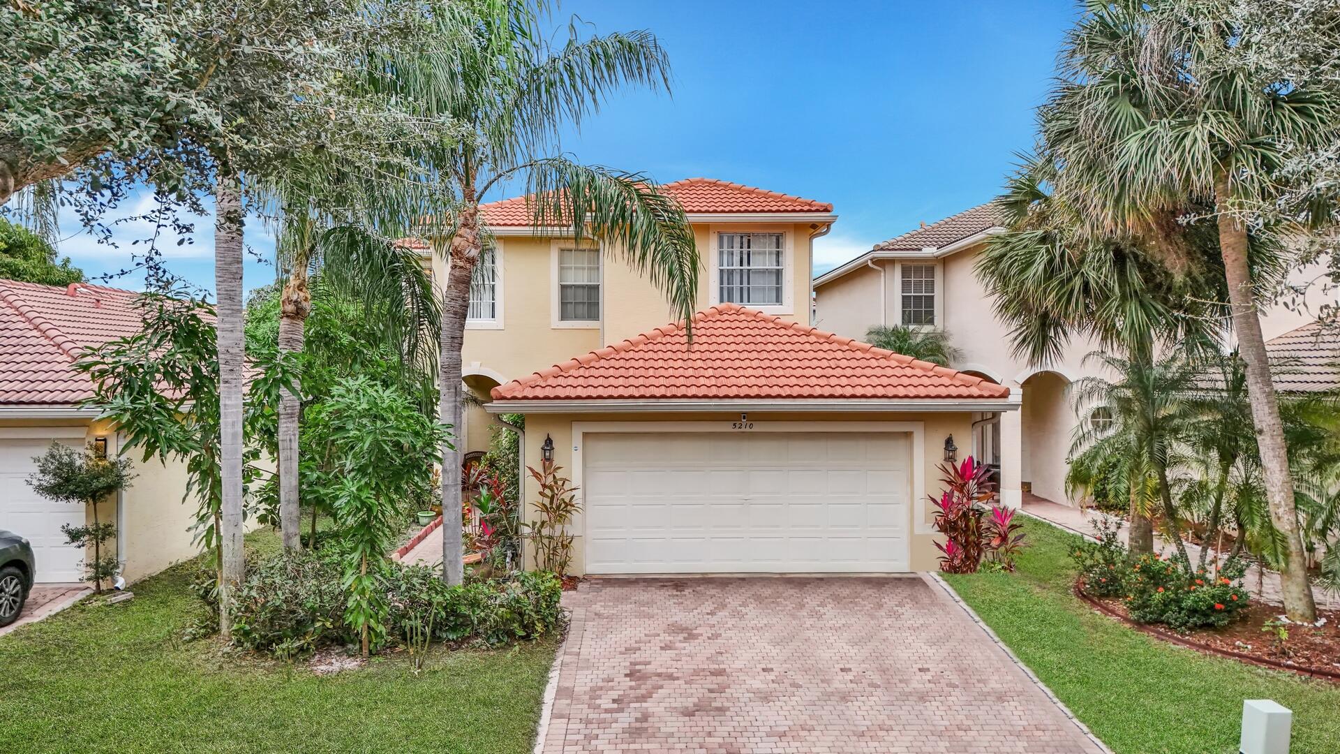 a front view of a house with a garden and palm trees