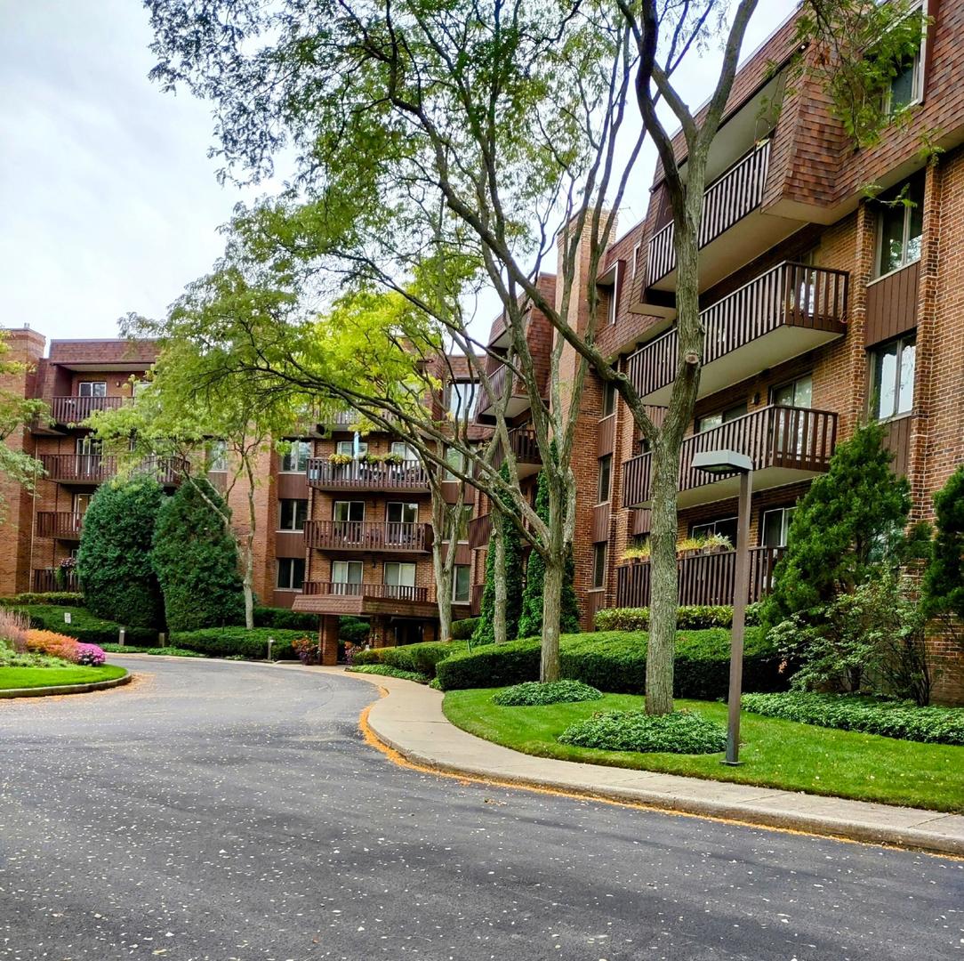 a view of a building with a yard and large trees