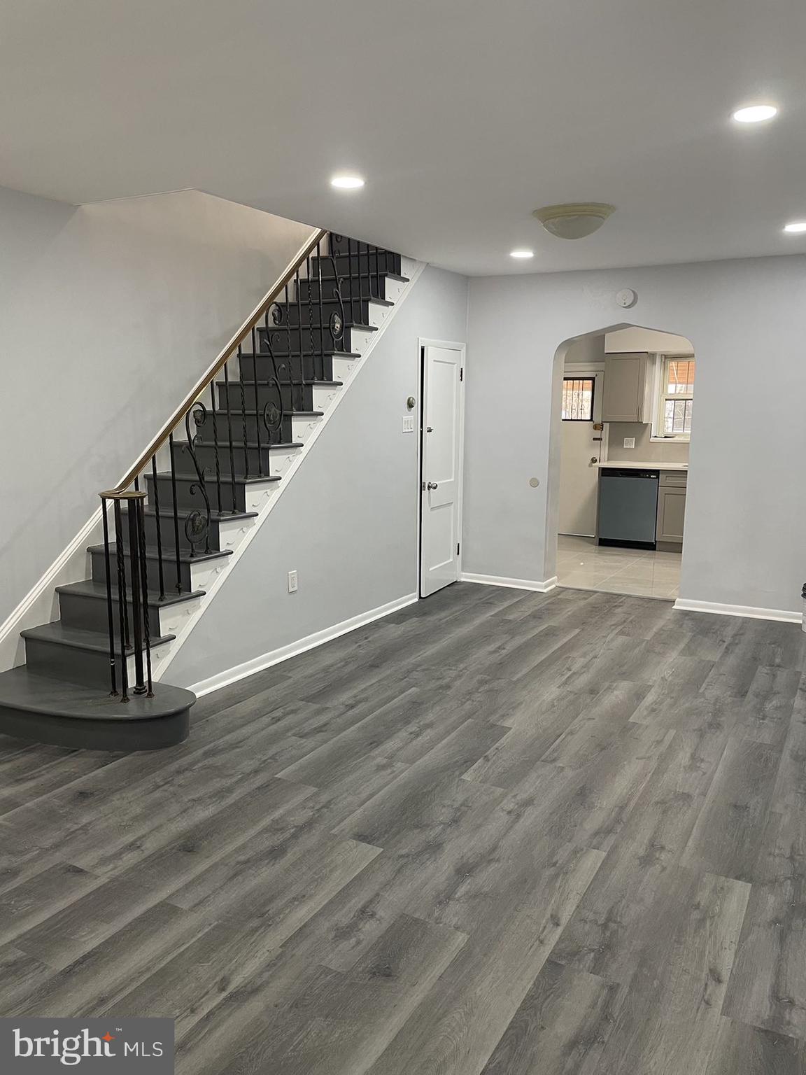 a view of an empty room with wooden floor and stairs