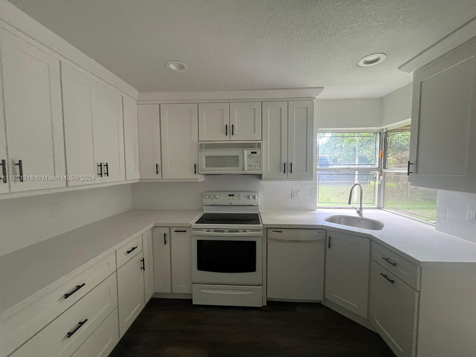 a kitchen with cabinets appliances a sink and a window