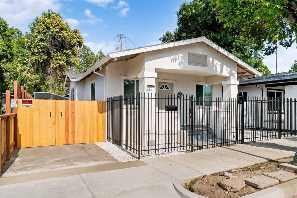 a view of a white house with wooden fence and large trees