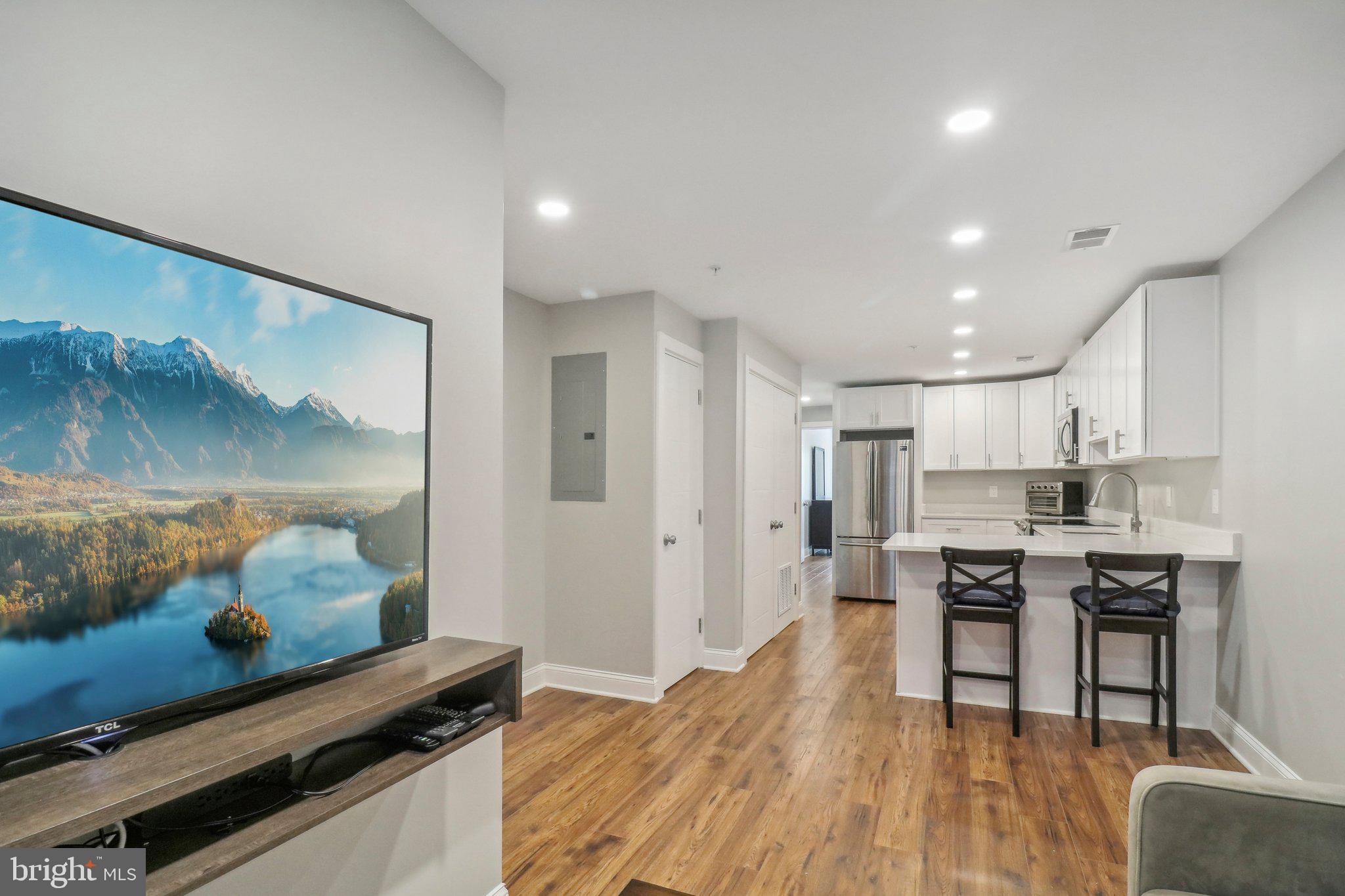 a living room with stainless steel appliances kitchen island granite countertop furniture and a wooden floor