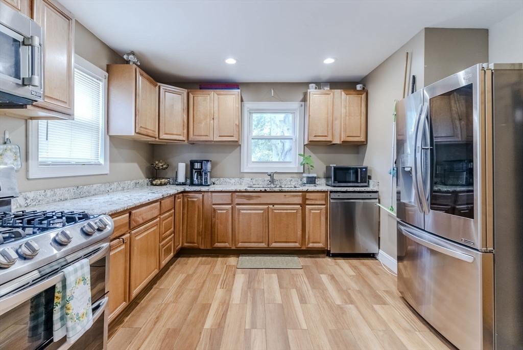 a kitchen with granite countertop a refrigerator stove top oven and sink