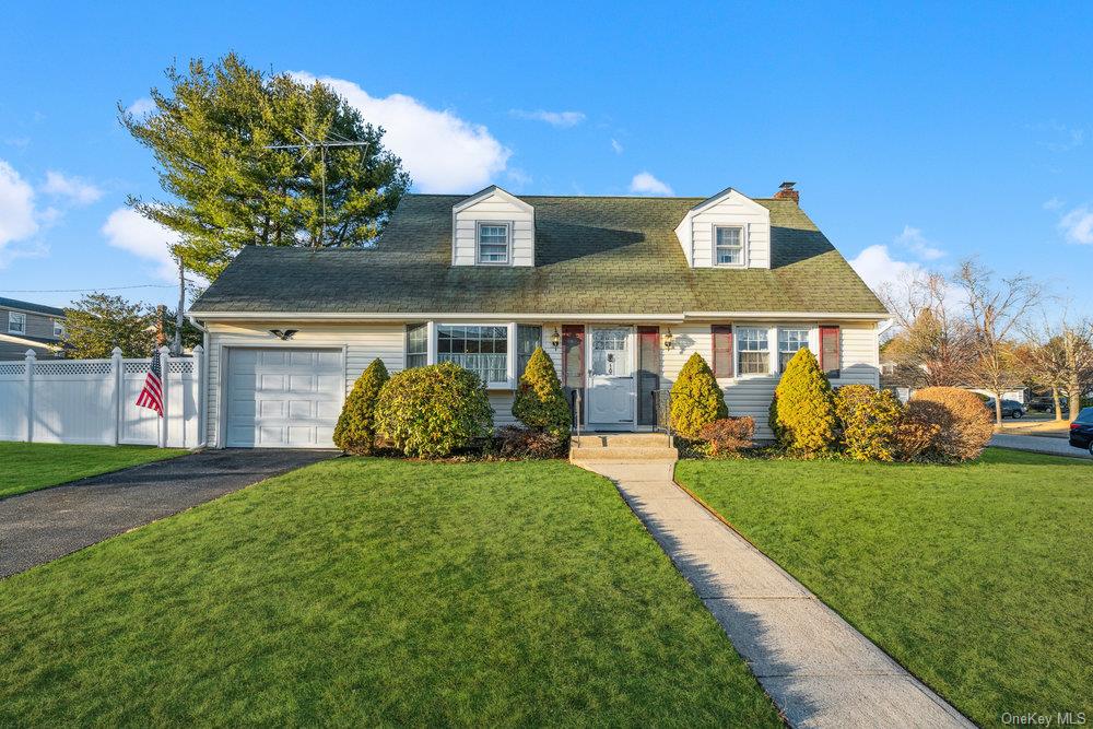 Cape cod home with a garage and a front lawn