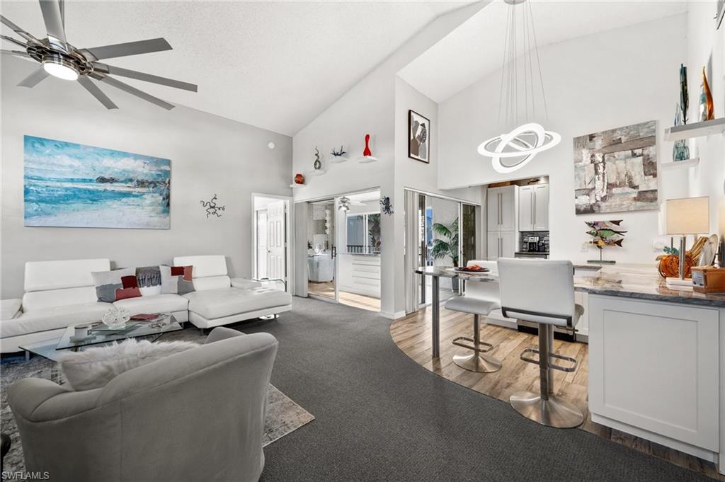 Living room with ceiling fan, high vaulted ceiling, and light hardwood / wood-style floors