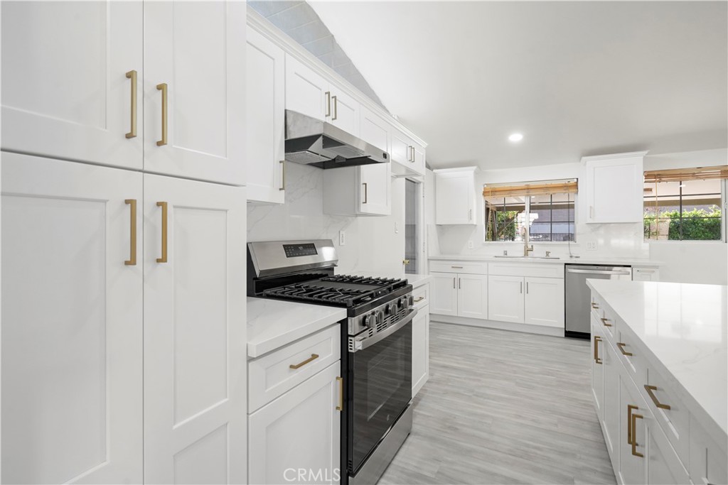 a kitchen with stainless steel appliances a white cabinets and wooden floor