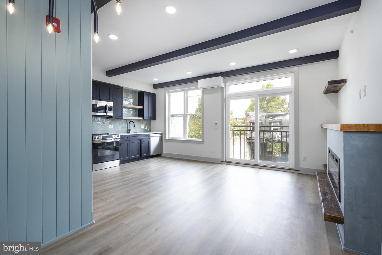 a view of a kitchen with furniture a refrigerator and wooden floor