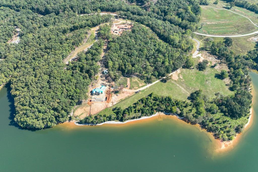 an aerial view of a residential houses with outdoor space and trees all around