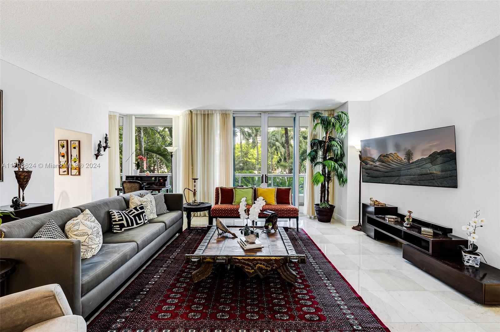 a living room with furniture floor to ceiling window and a flat screen tv