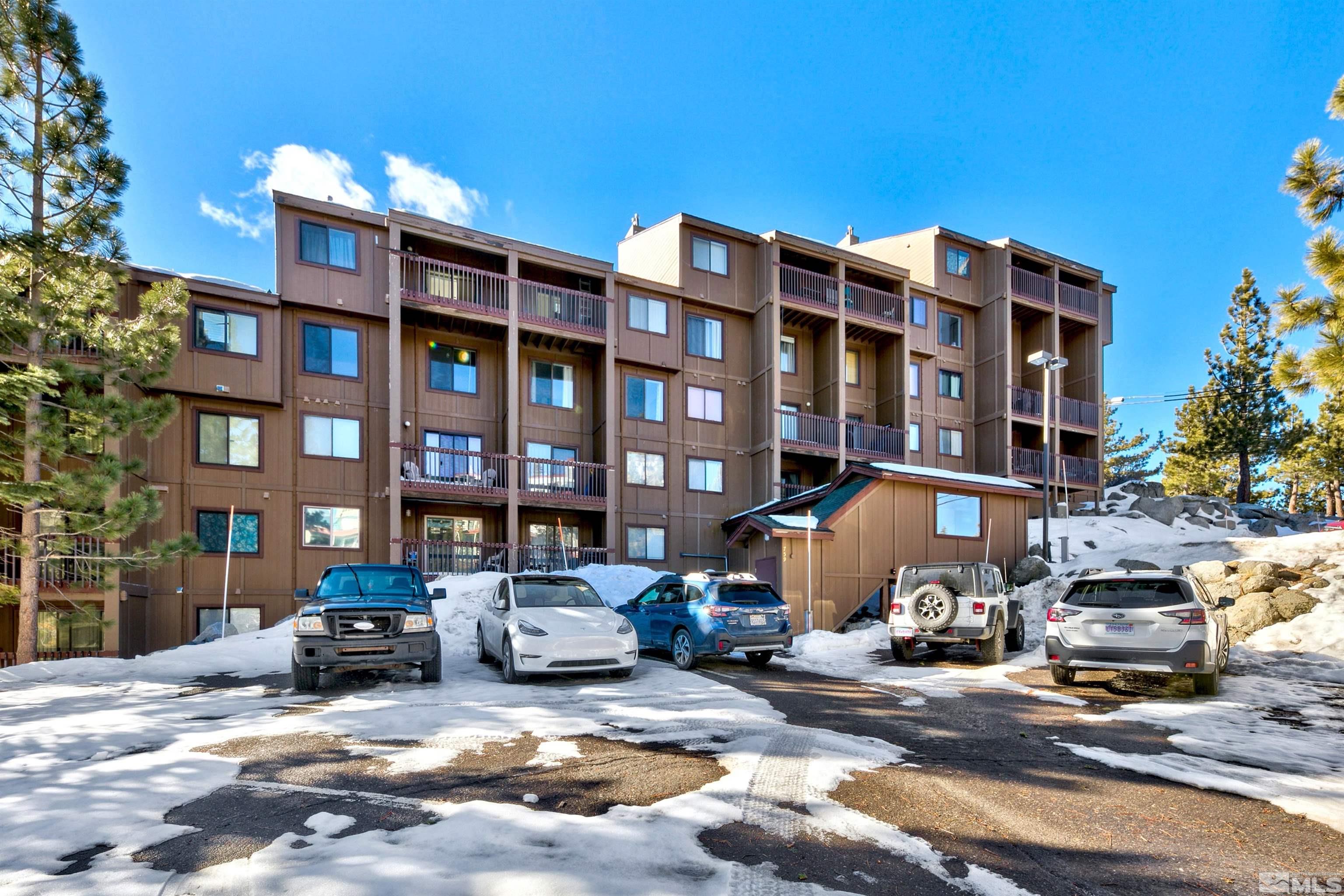 a front view of a building with cars parked