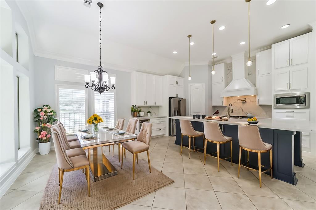 a dining room filled with furniture a chandelier and kitchen view