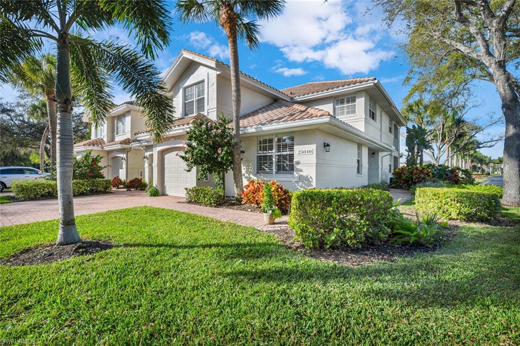 a view of a white house next to a yard with palm trees