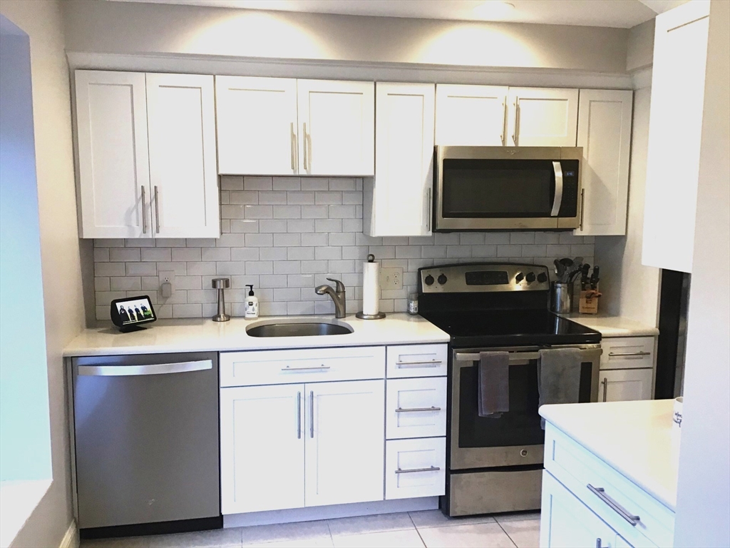 a kitchen with cabinets stainless steel appliances and wooden floor