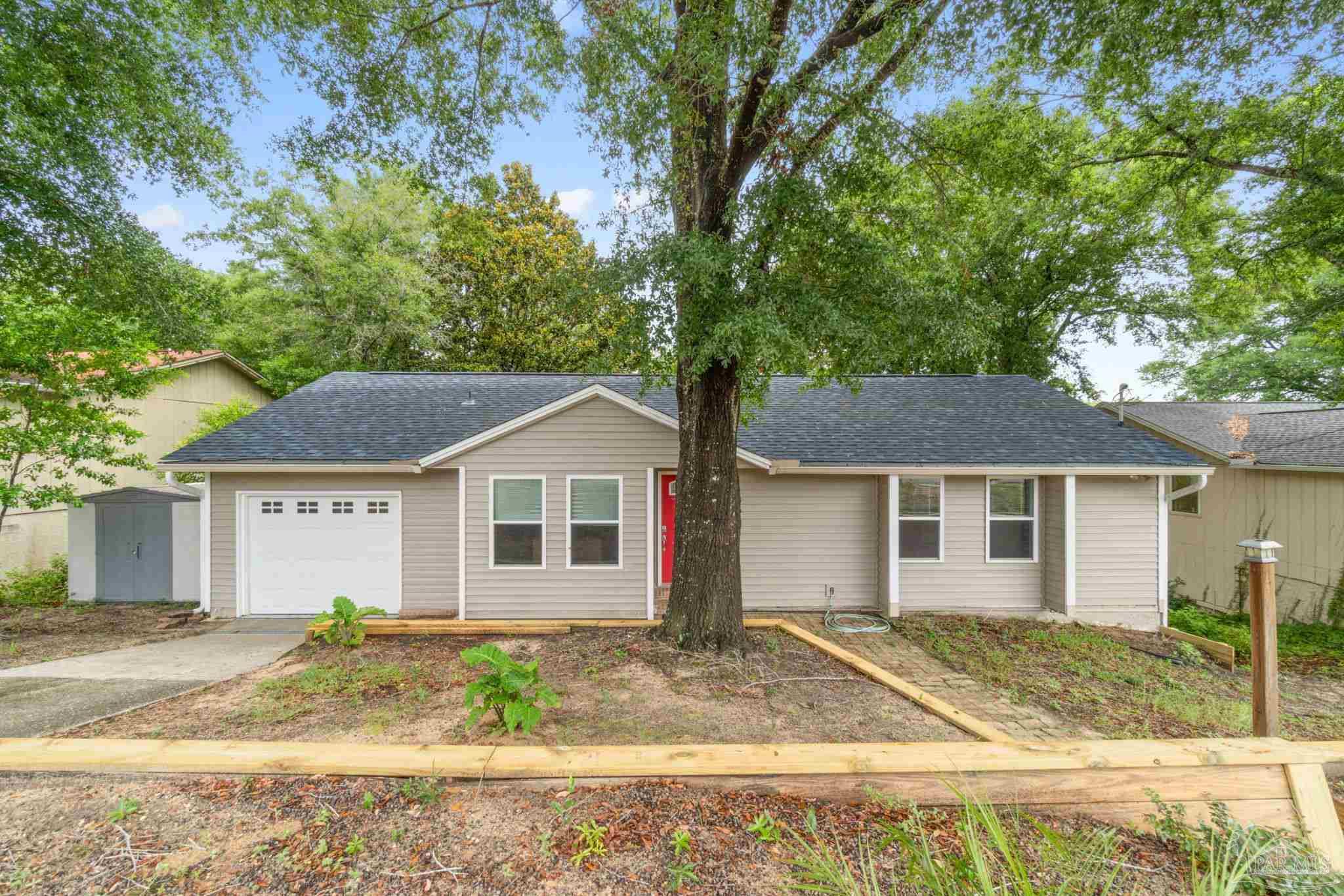 a view of a yard in front of a house with large tree