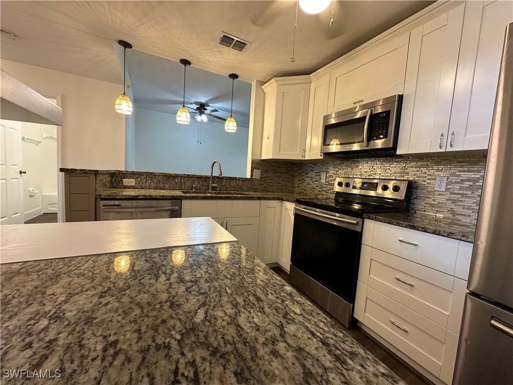 a kitchen with stainless steel appliances granite countertop a stove a sink and a microwave