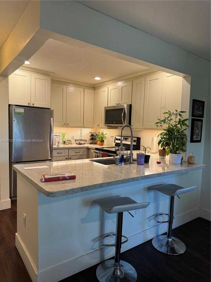 a kitchen with stainless steel appliances granite countertop a sink refrigerator and microwave