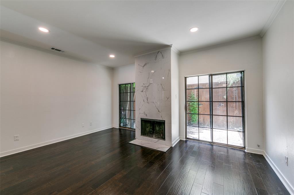 an empty room with wooden floor fireplace and windows