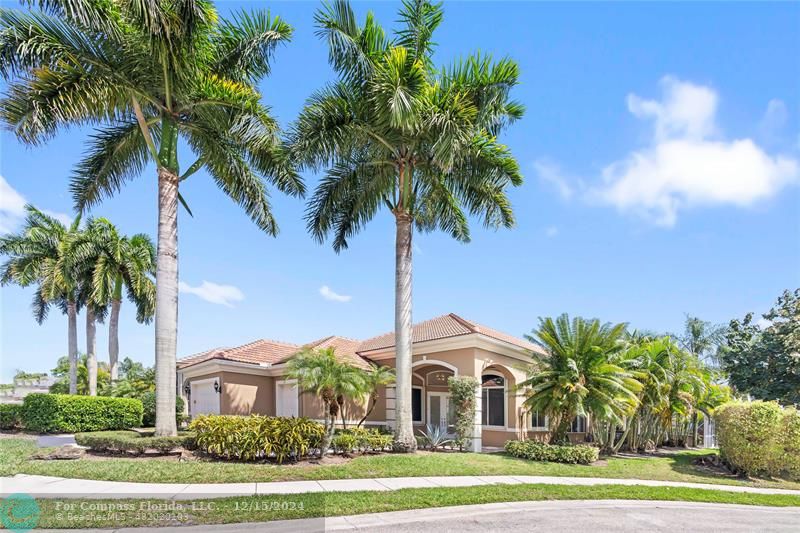 a view of a white house with a yard and palm trees