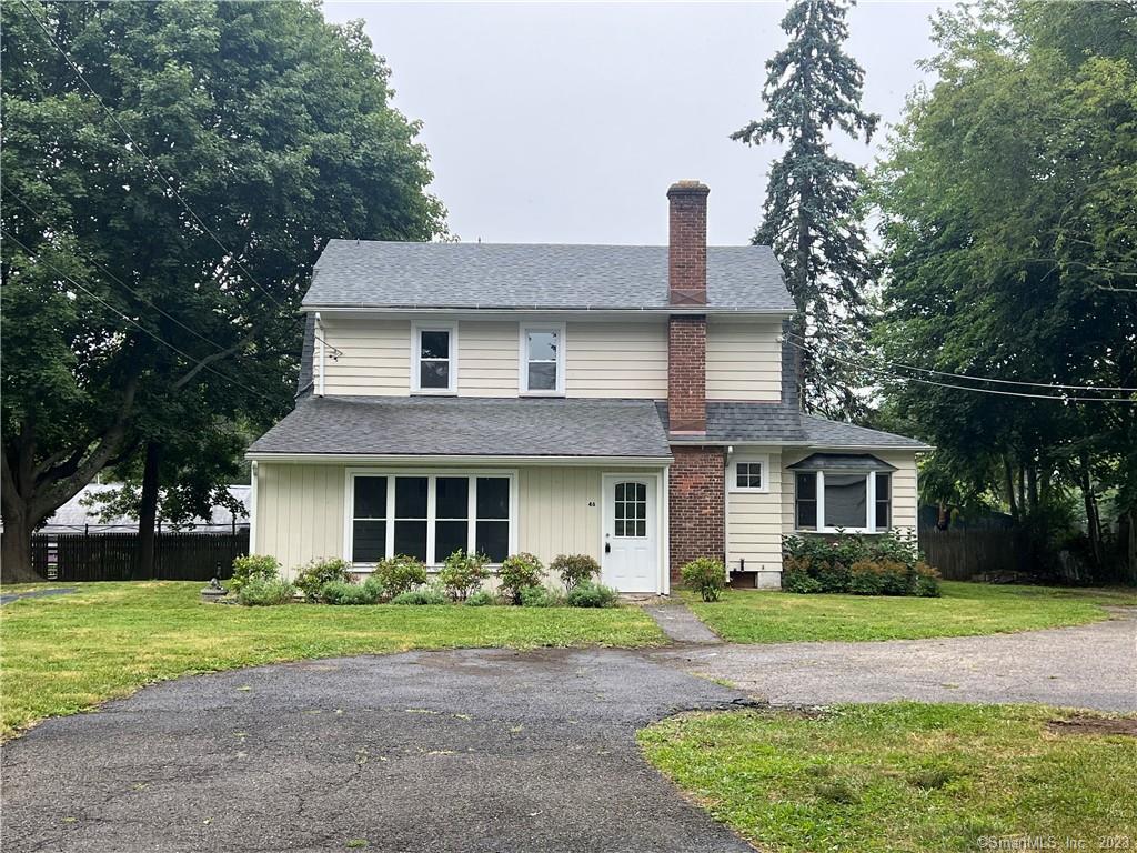 a front view of a house with a yard and trees