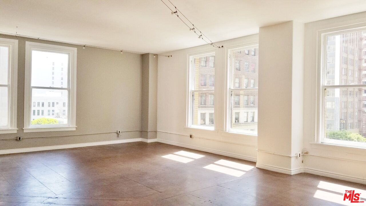 a view of an empty room with a window and wooden floor