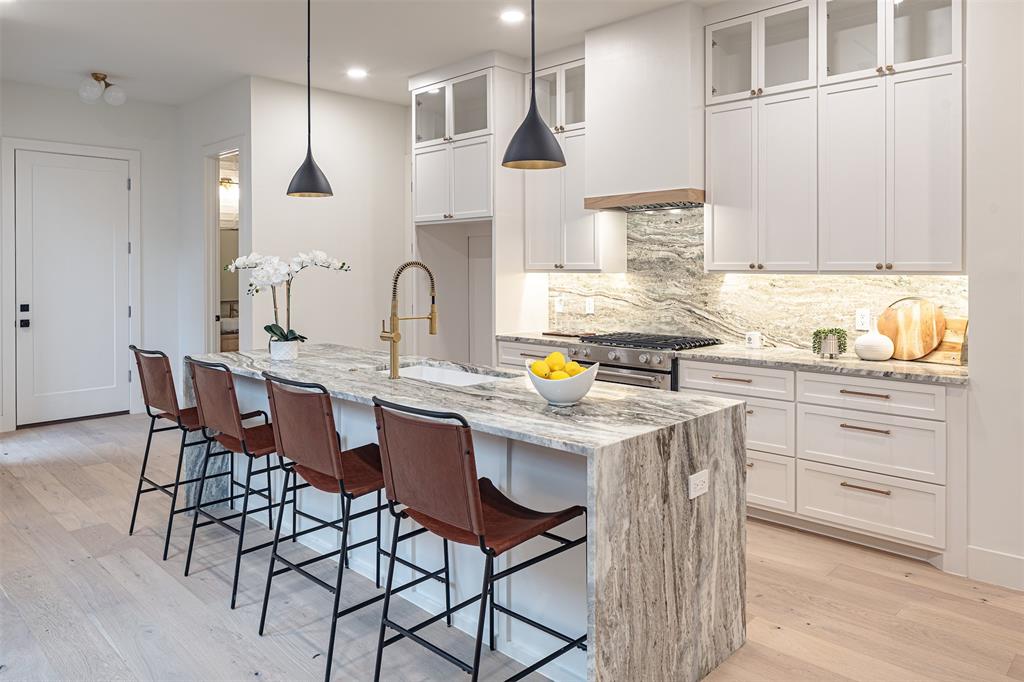 a kitchen with stainless steel appliances kitchen island granite countertop a table chairs sink and cabinets