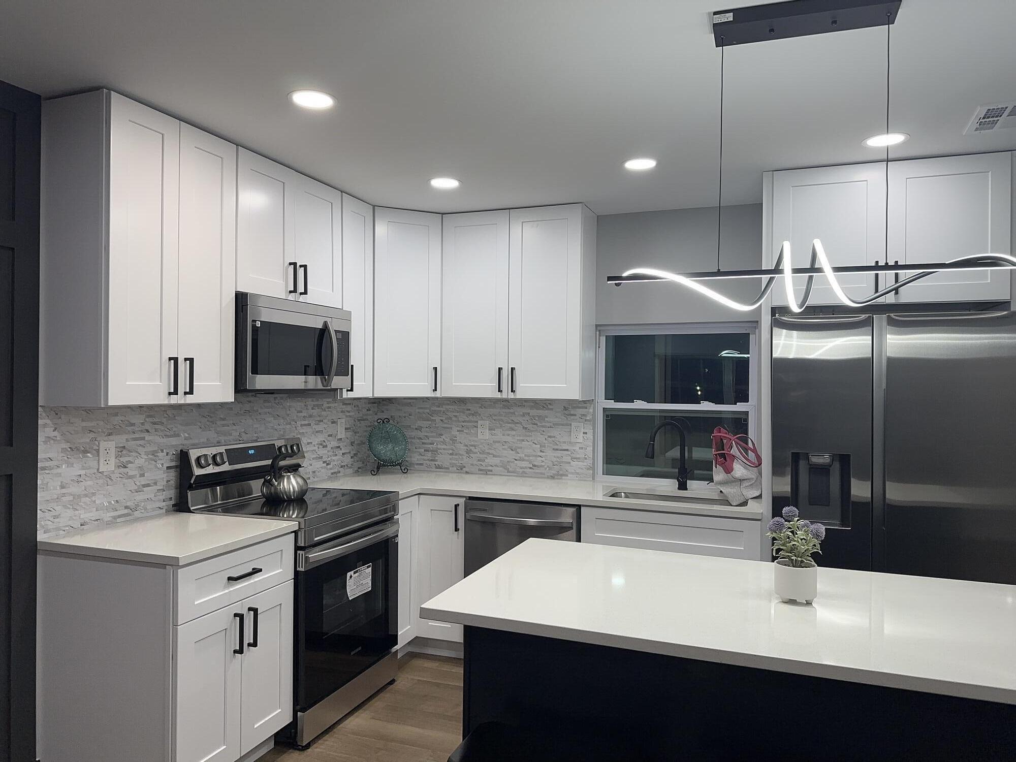 a kitchen with kitchen island granite countertop a sink and a stove top oven with wooden floor