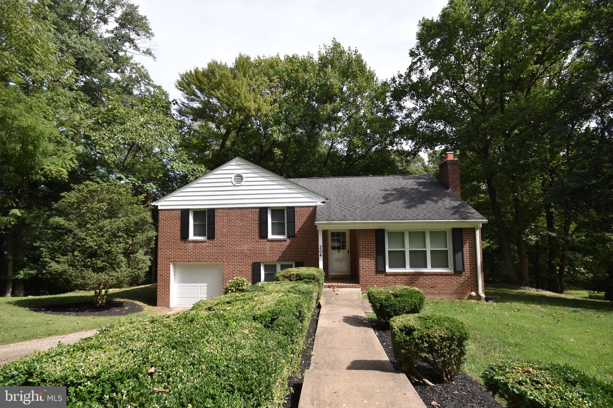 a front view of a house with a yard and trees