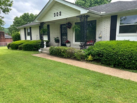 a view of a house with brick walls and a yard with plants