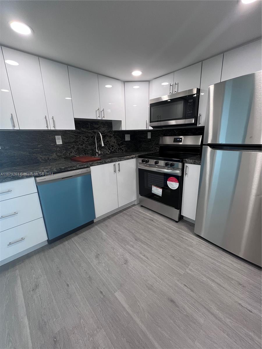 a kitchen with granite countertop a refrigerator and a stove top oven