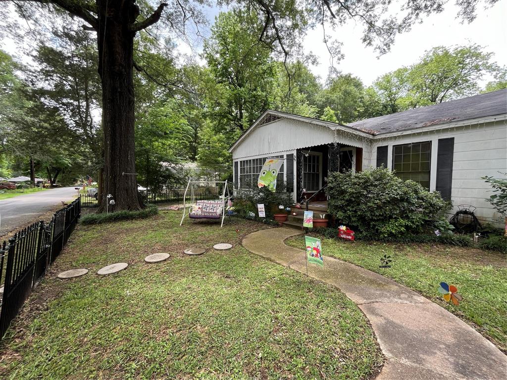 a view of a backyard with table and chairs potted plants and large tree