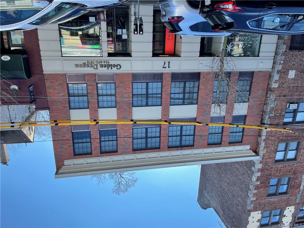 a front view of a building with lot of cars and trees