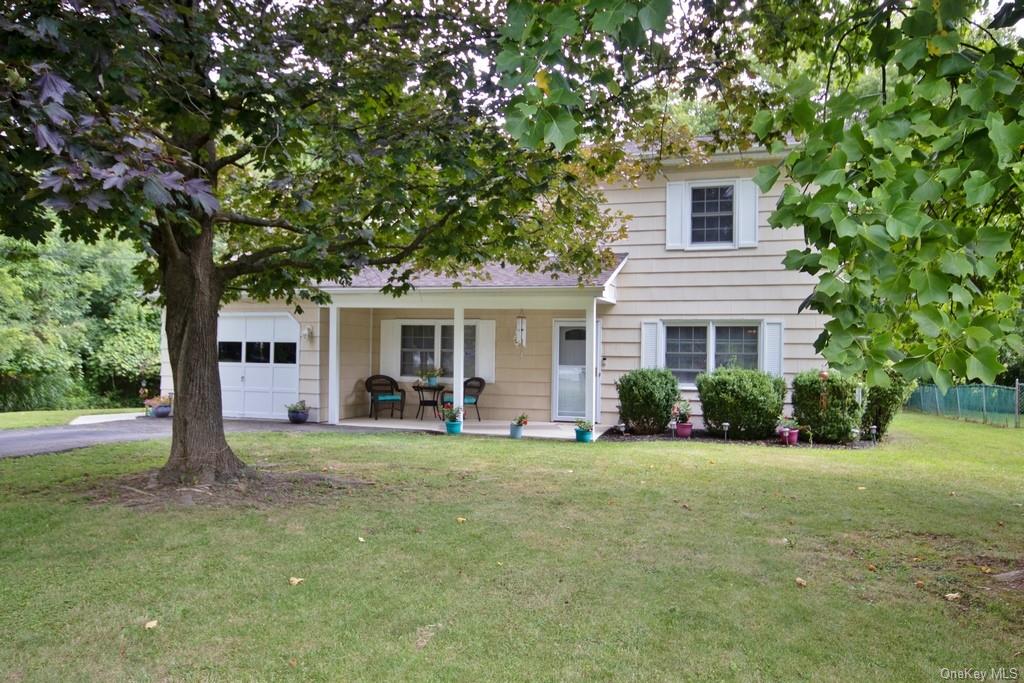 View of front facade with a garage, a front lawn, and covered porch