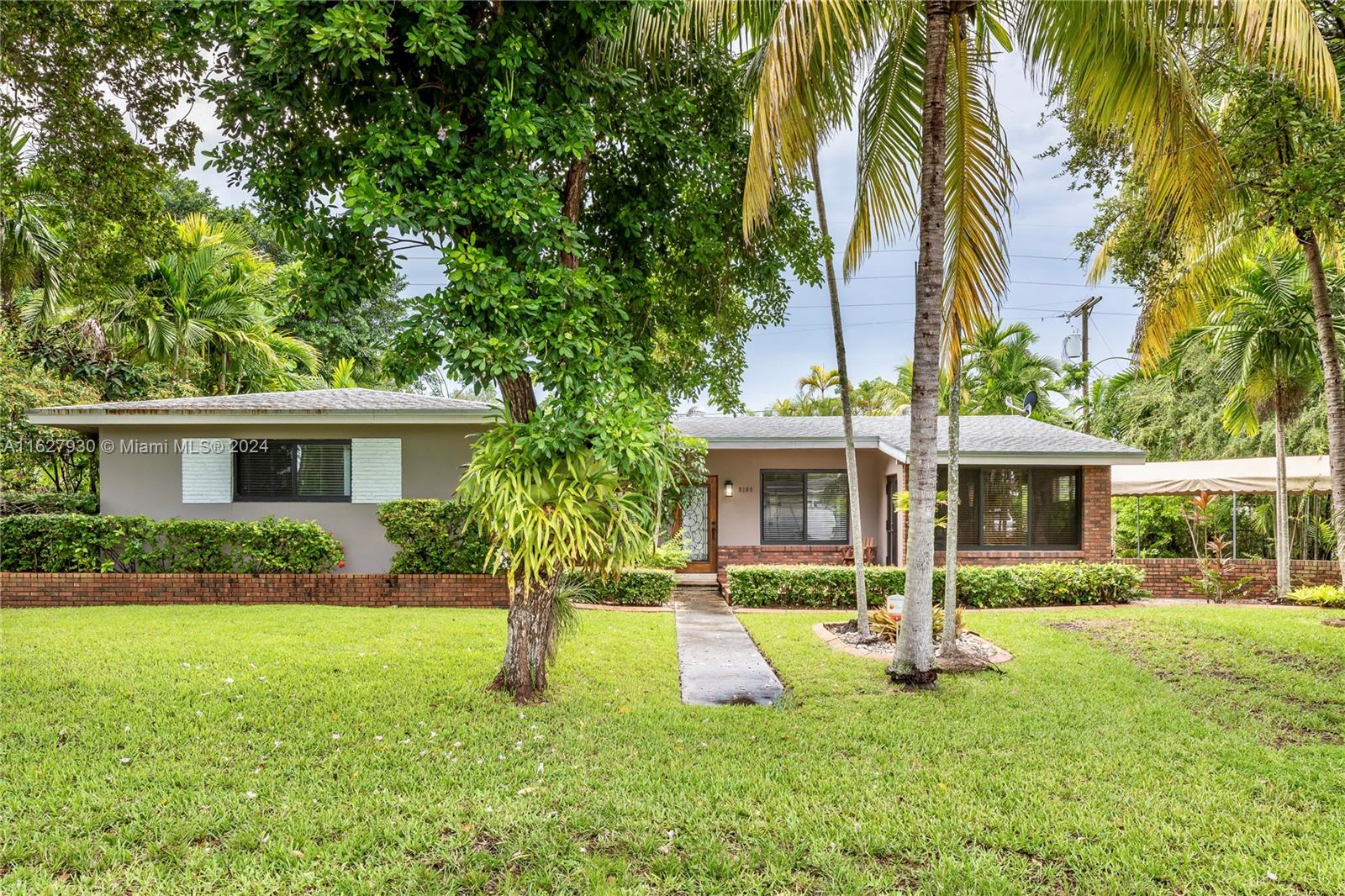 a view of a house with a yard and palm trees