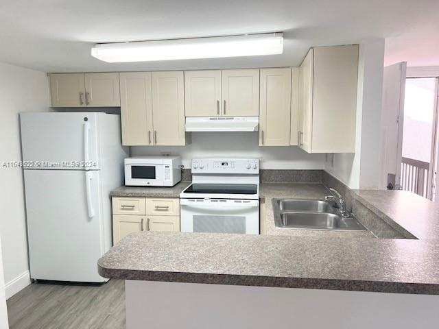 a kitchen with kitchen island a stove a refrigerator and a sink with wooden floors