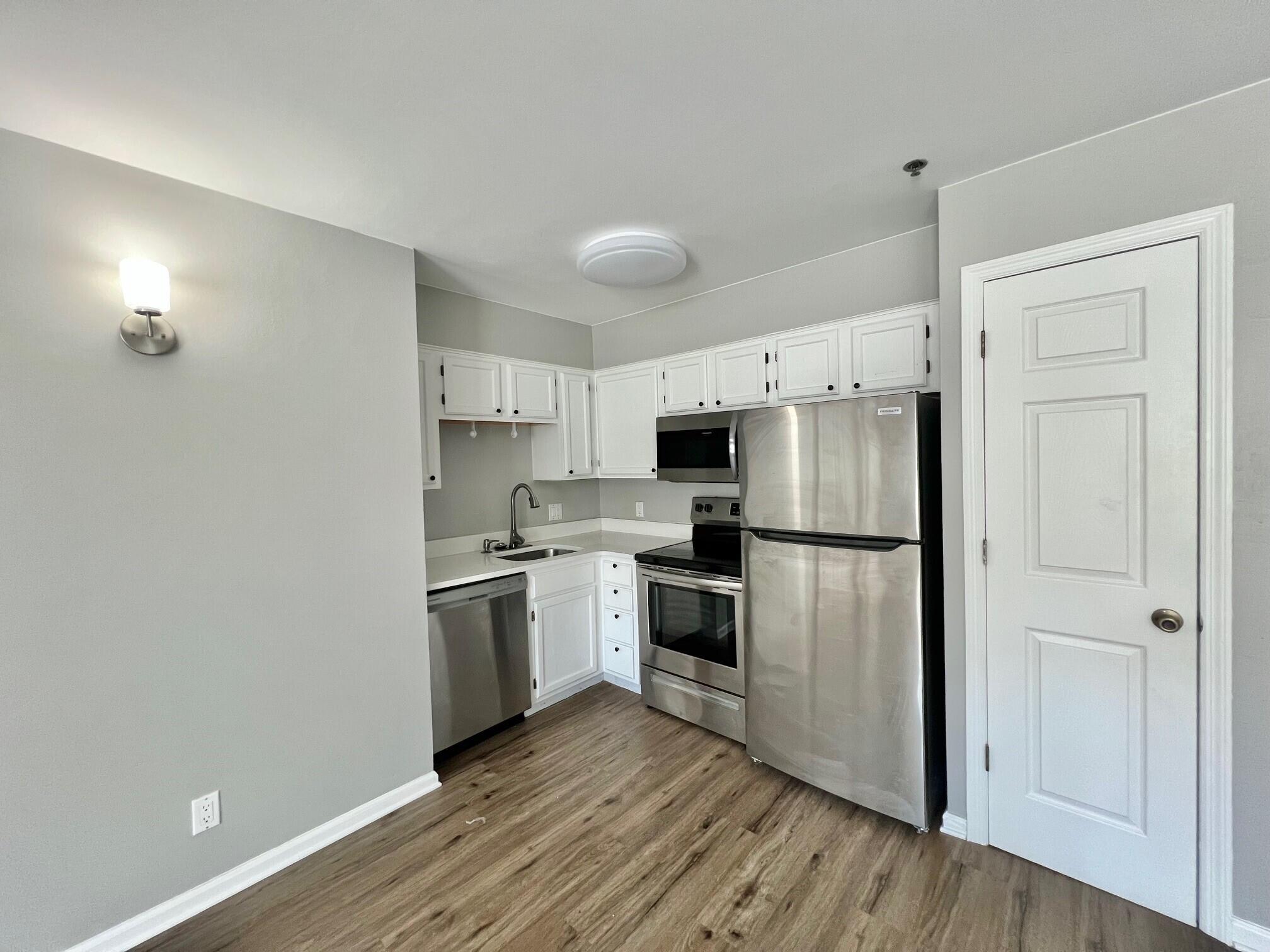 a kitchen with a refrigerator a stove top oven and white cabinets