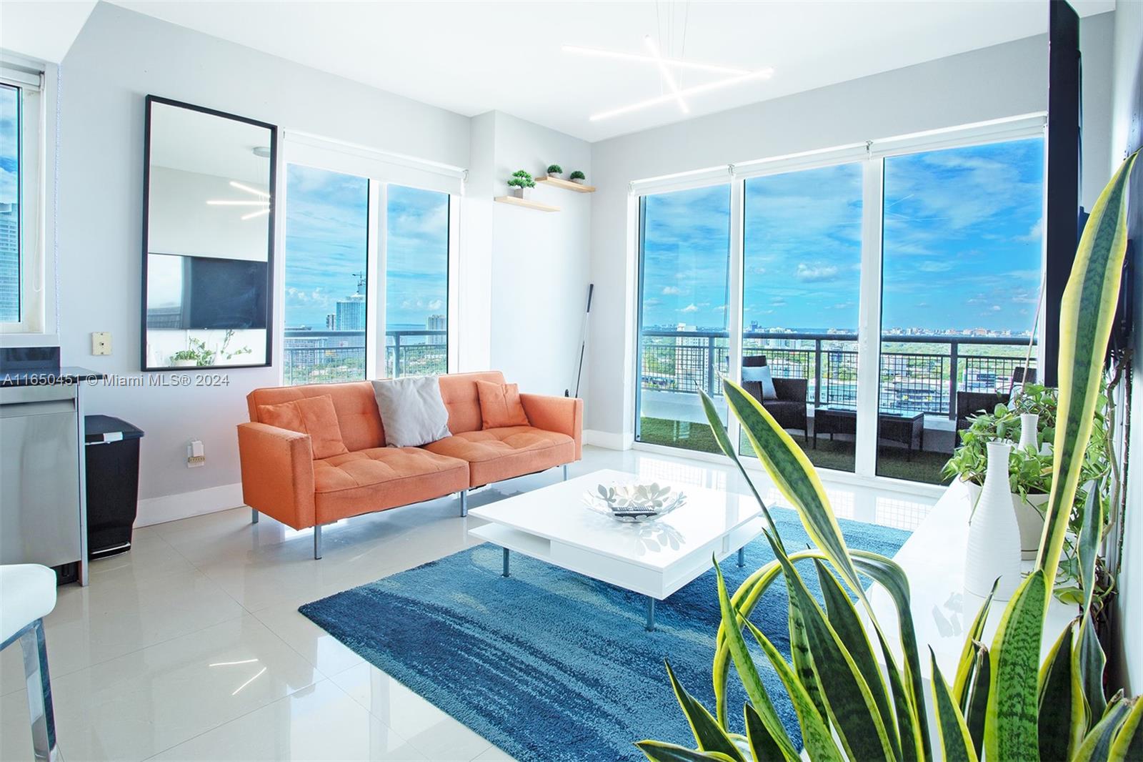 a living room with furniture a large window and wooden floor