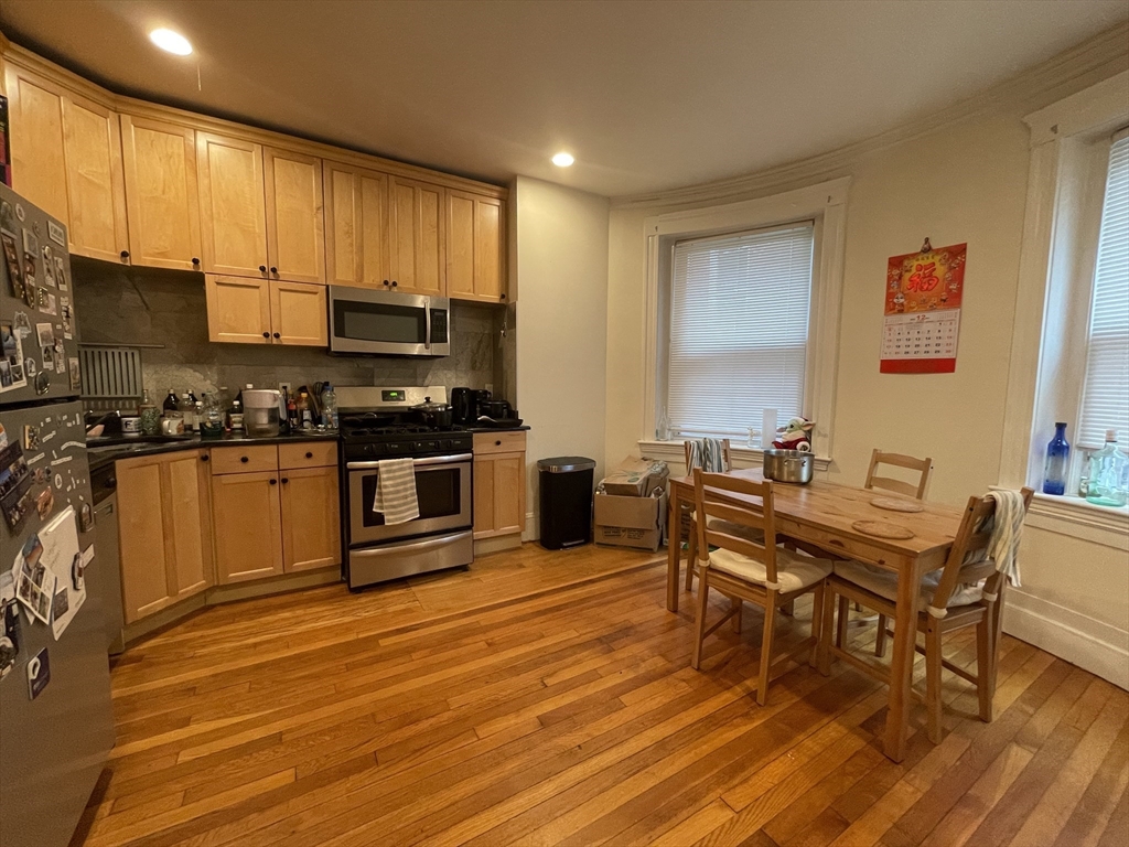 a kitchen with stainless steel appliances a stove a sink a microwave and wooden floors