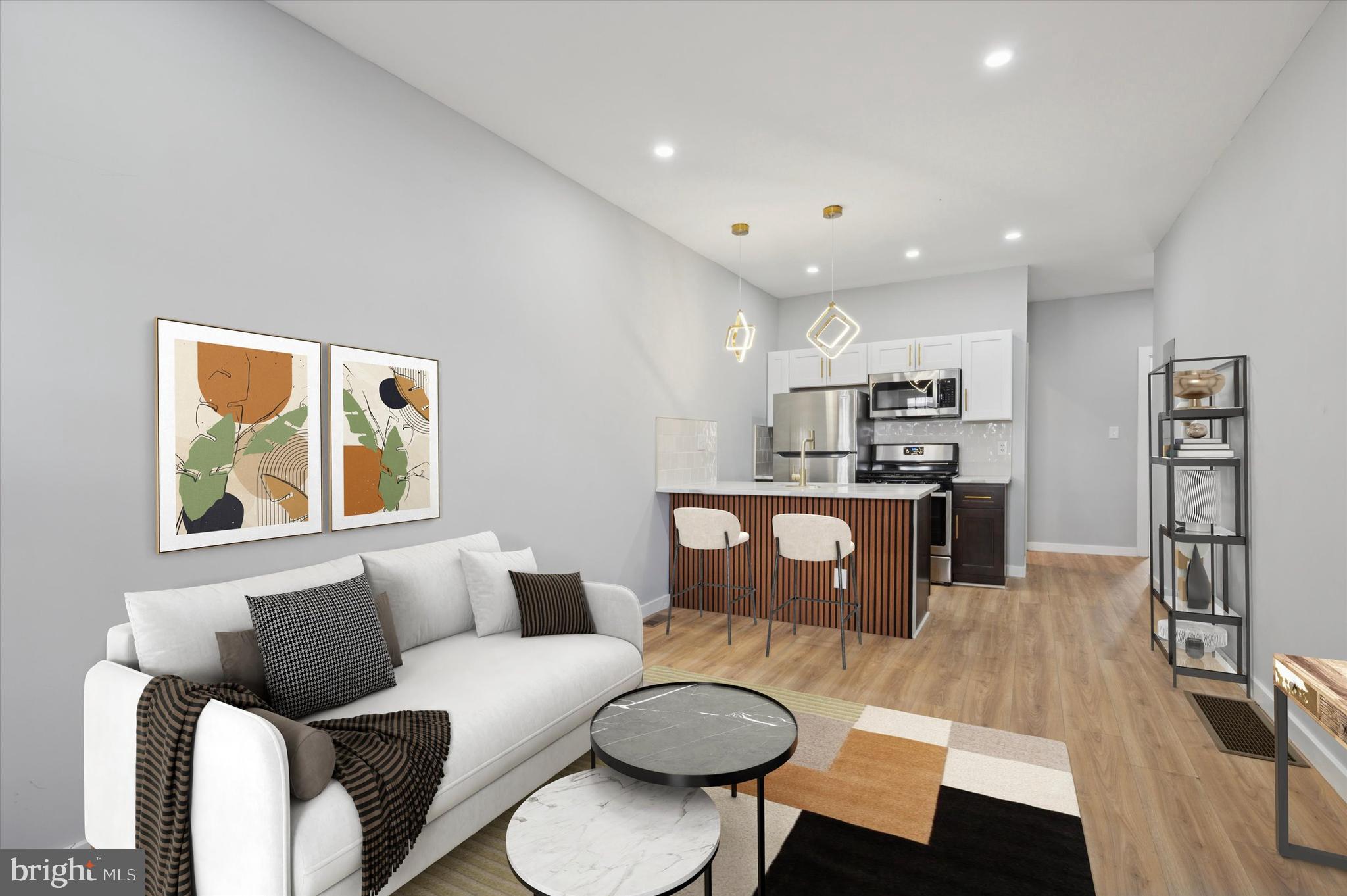 a living room with stainless steel appliances furniture a rug and a kitchen view