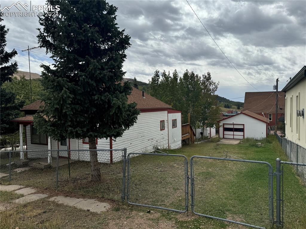 a view of a white house with a big yard and large tree