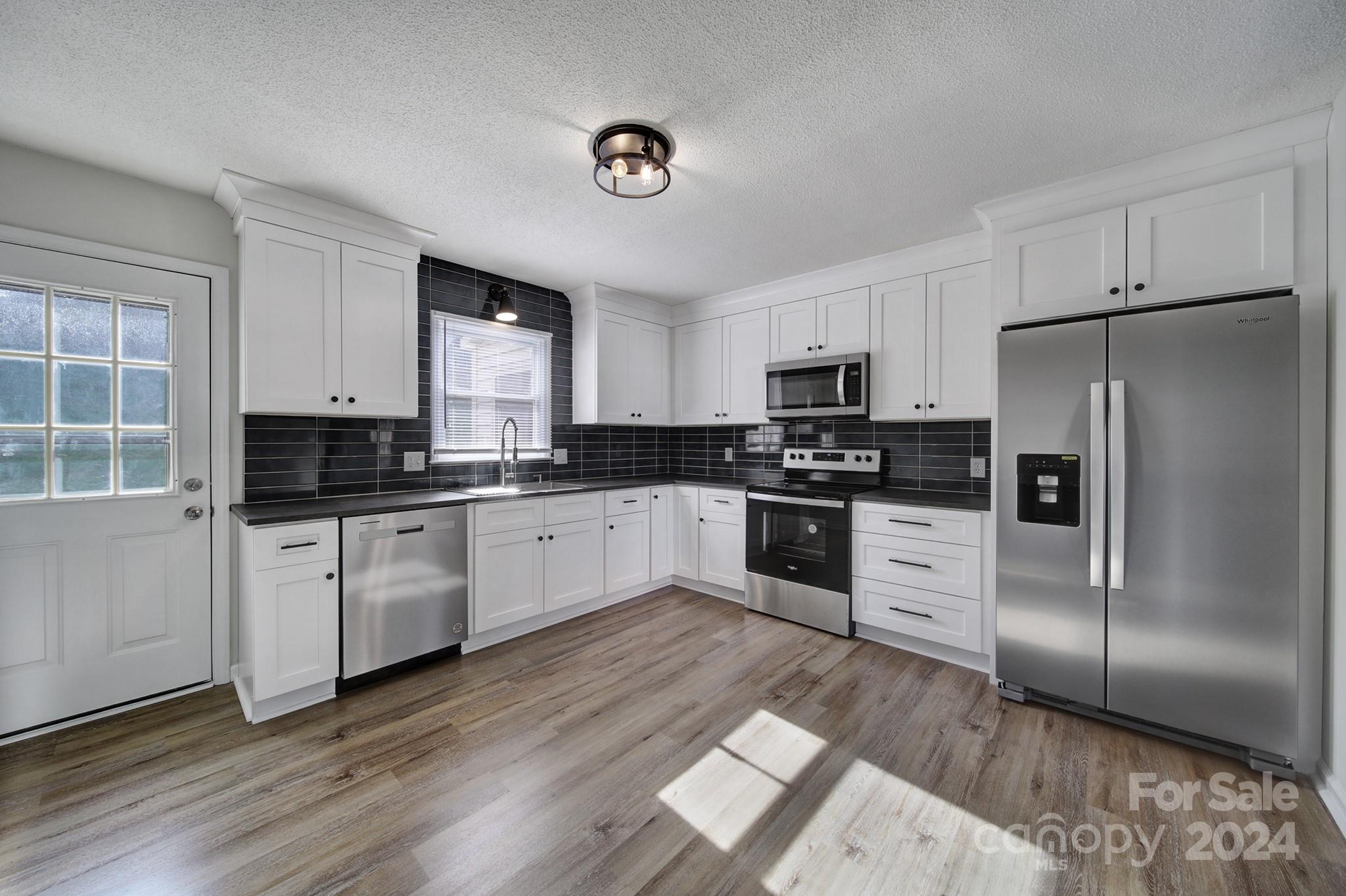 a kitchen with granite countertop a refrigerator stove top oven and sink