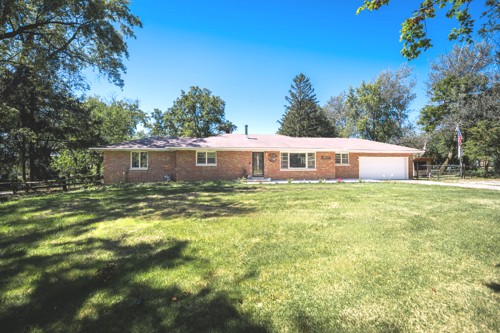 a front view of house with yard and trees in the background