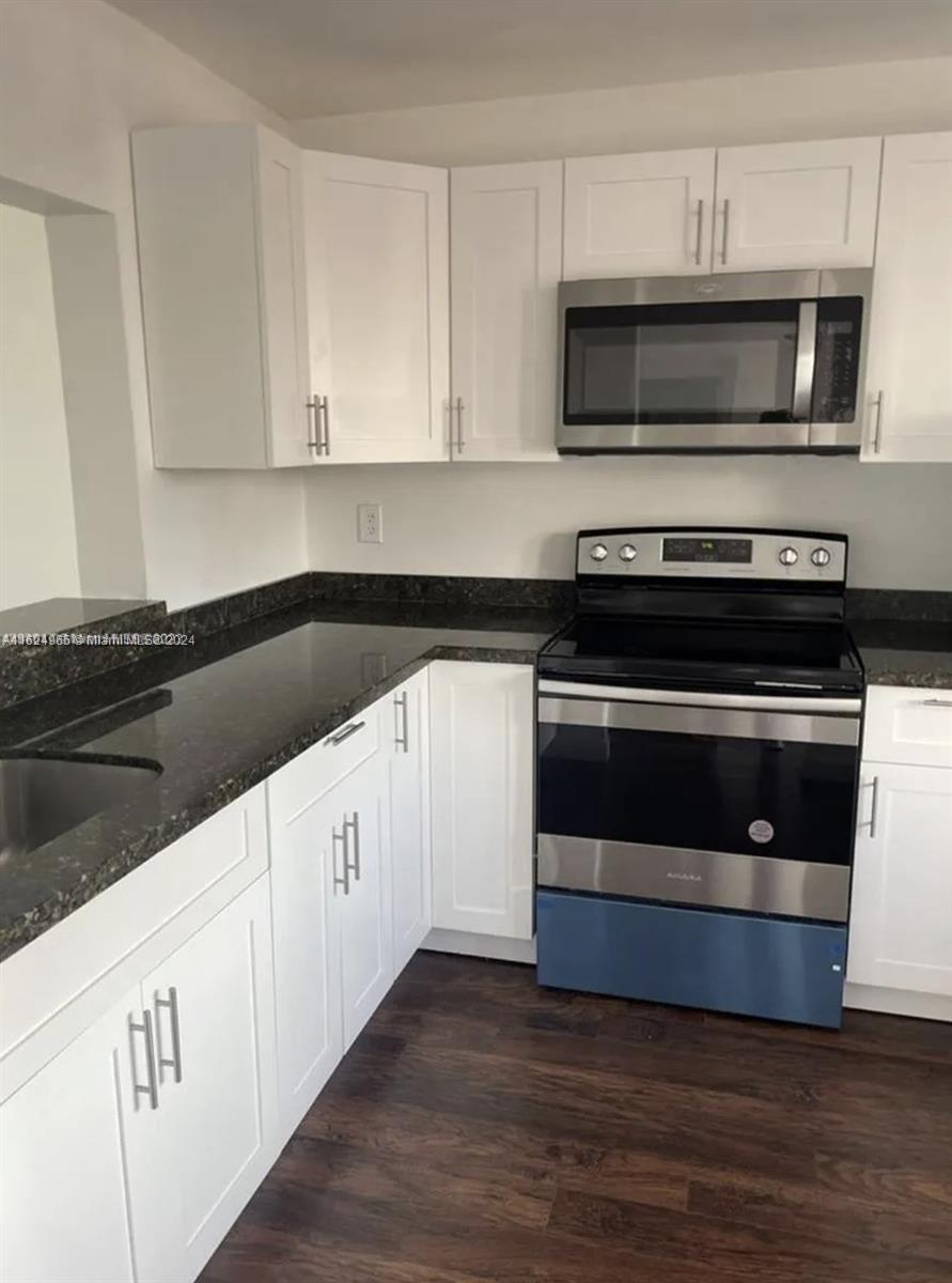 a kitchen with granite countertop white cabinets and stainless steel appliances