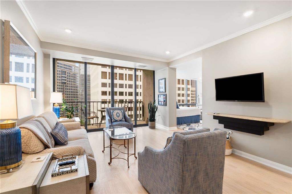 a living room with furniture a flat screen tv and a floor to ceiling window