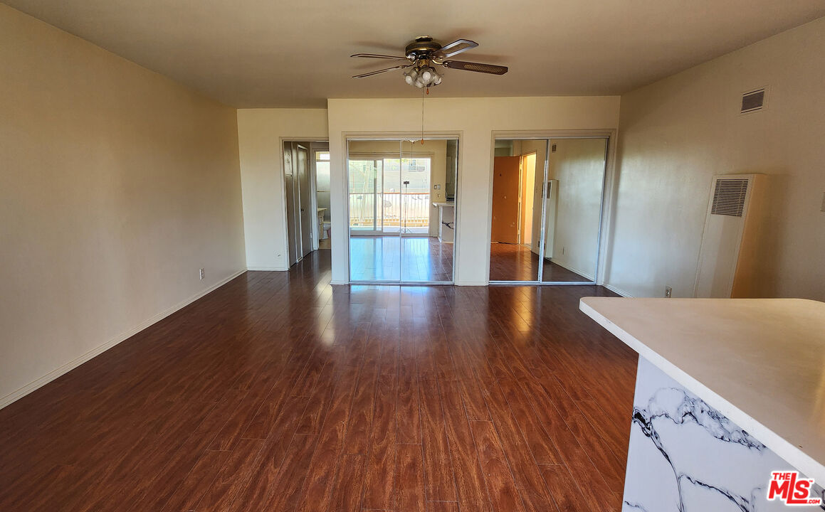 a view of a room with wooden floor and ceiling fan