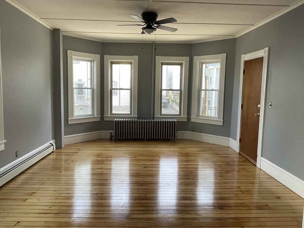 a view of an empty room with window and wooden floor