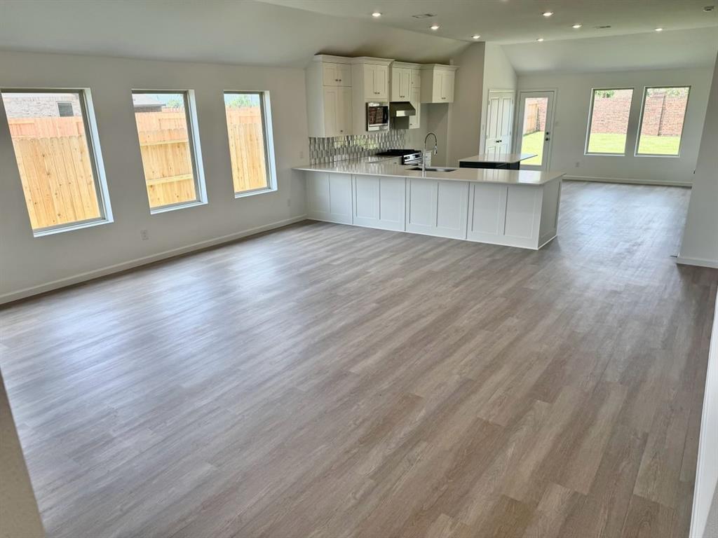 a large kitchen with stainless steel appliances granite countertop a large counter top and a wooden floors