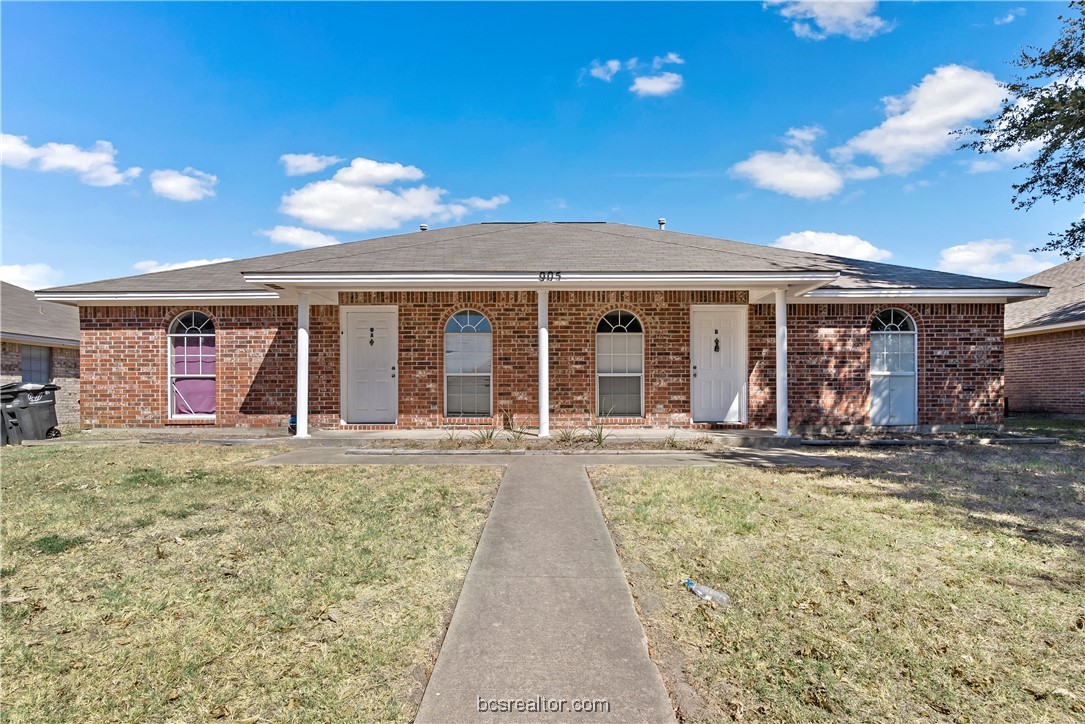 front view of a brick house with a yard