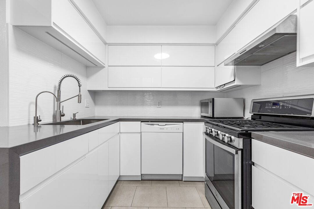 a kitchen with white cabinets and appliances