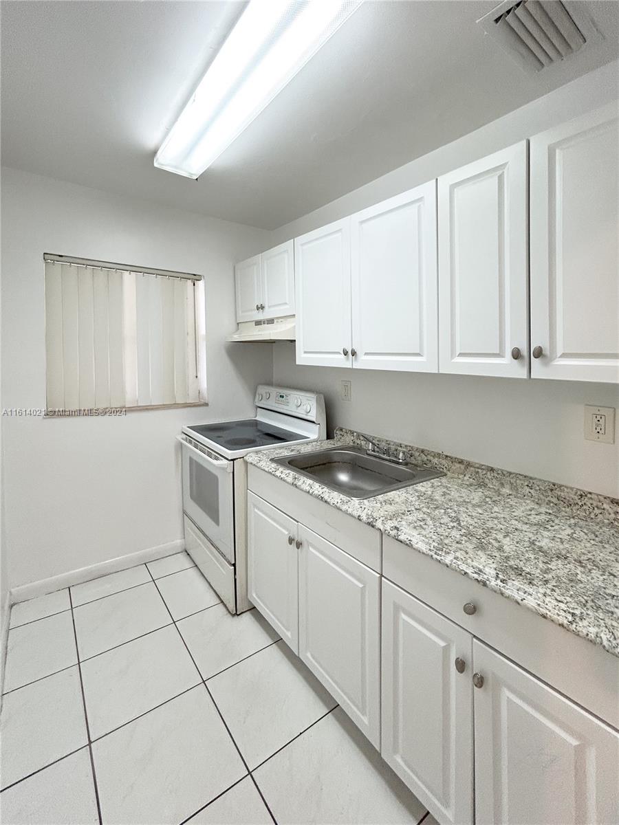 a kitchen with granite countertop white cabinets and white appliances